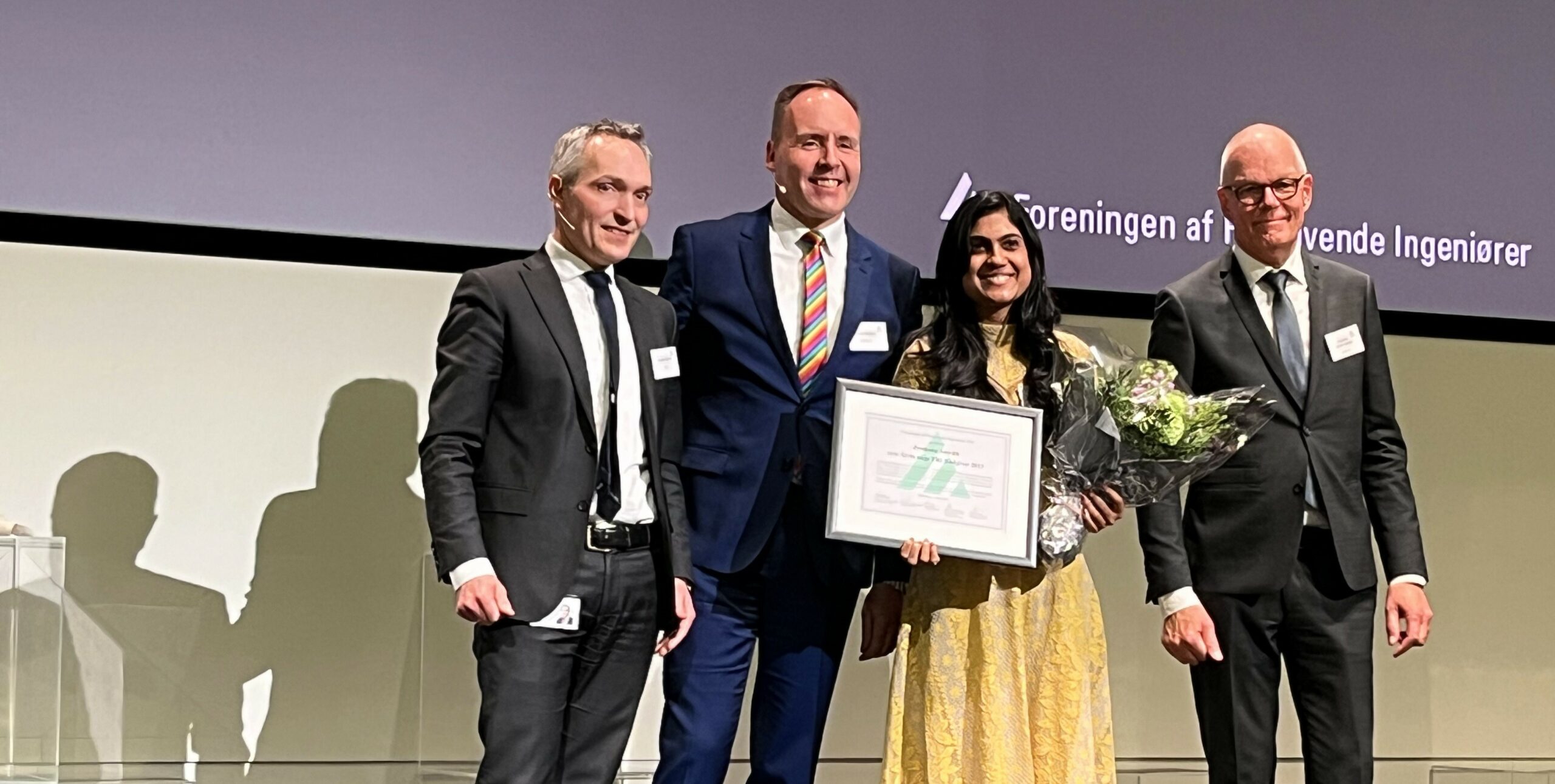 Fire mennesker p en scene med en award