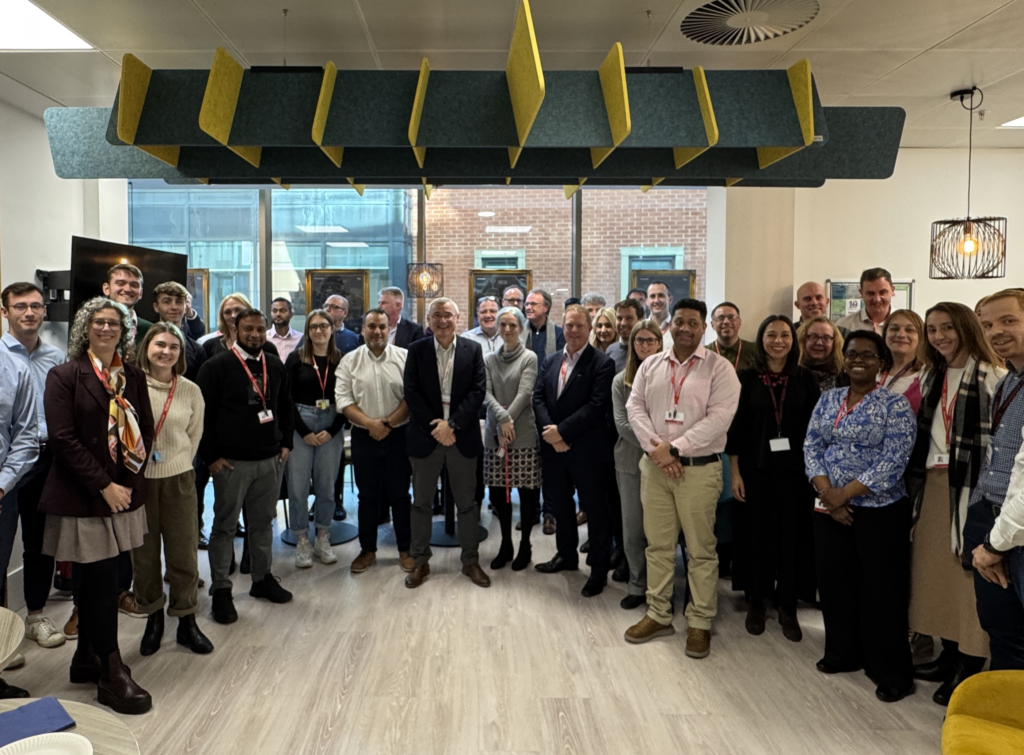 Jean-Charles Vollery is pictured standing in the middle of colleagues in a large group photo in the Manchester office.